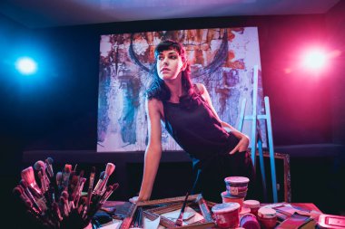 Stüdyoda iş yerinde genç sanatçı. Arka planda büyük tuval