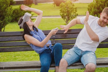 Genç çift sanal gerçeklik gözlükle sokakta bir oyun oynuyor. VR kulaklık.