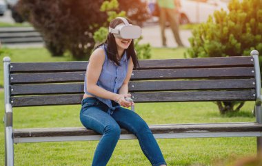 Çekici genç kız sokakta sanal gerçeklik gözlük takan bir oyun oynuyor. VR kulaklık.