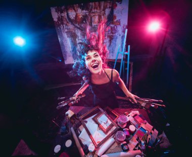 Stüdyoda iş yerinde genç sanatçı. Arka planda büyük tuval