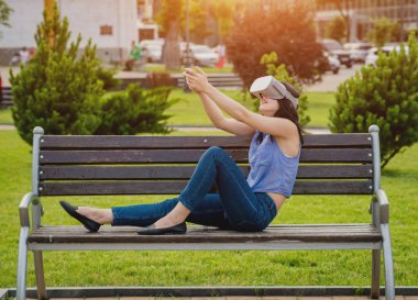 Çekici genç kız sokakta sanal gerçeklik gözlük takan bir oyun oynuyor. VR kulaklık.