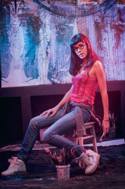 Stüdyoda iş yerinde genç sanatçı. Arka planda büyük tuval