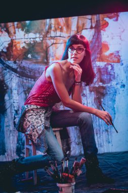 Stüdyoda iş yerinde genç sanatçı. Arka planda büyük tuval