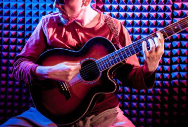 Akustik gitar ses kayıt Studio oynayan genç adam. Modern arka plan