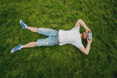 Genç sakallı adam gözlük çim üzerinde yalan sanal gerçekliğin bir oyun oynar. VR kulaklık