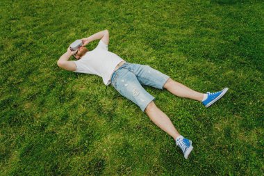 Genç sakallı adam gözlük çim üzerinde yalan sanal gerçekliğin bir oyun oynar. VR kulaklık