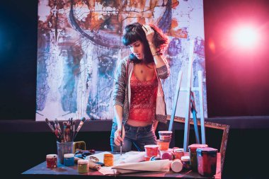 Stüdyoda iş yerinde genç sanatçı. Arka planda büyük tuval