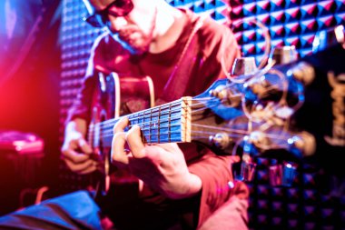 Akustik gitar ses kayıt Studio oynayan genç adam. Modern arka plan