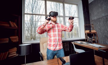 Sanal gerçeklik giyen genç sakallı adam ofiste gözlükler