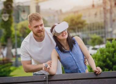 Genç çift sanal gerçeklik gözlükle sokakta bir oyun oynuyor. VR kulaklık.