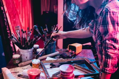 Stüdyoda iş yerinde genç sanatçı. Arka planda büyük tuval