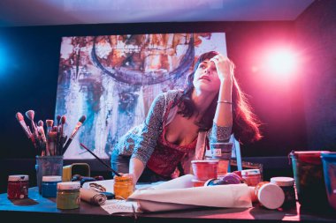 Stüdyoda iş yerinde genç sanatçı. Arka planda büyük tuval