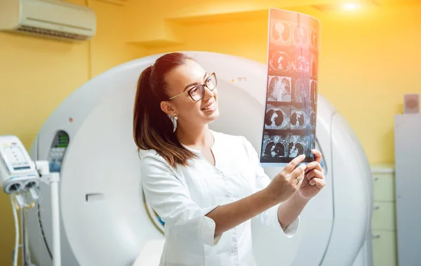 Female radiologist looking at x-ray in the room of computed tomography. Background