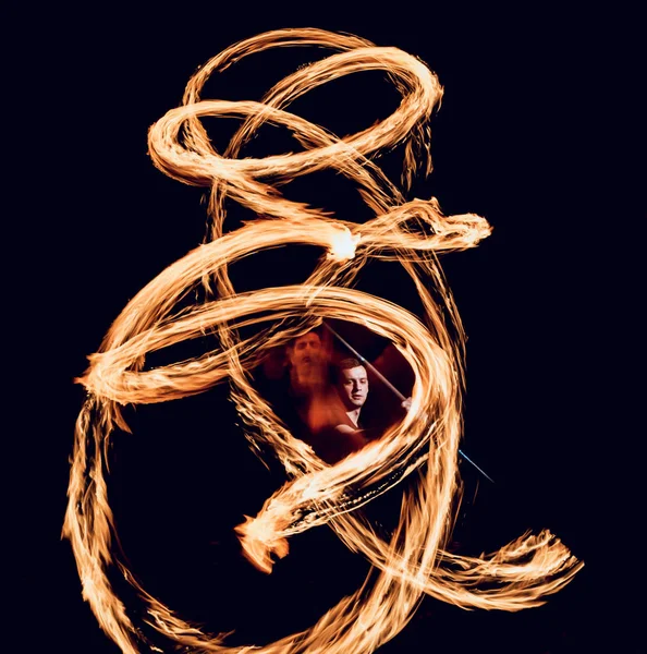 Gösteri yangın. Karanlıkta ateş performans gösteren genç adam.