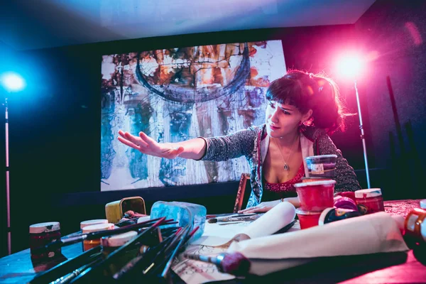 Stüdyoda iş yerinde genç sanatçı. Arka planda büyük tuval