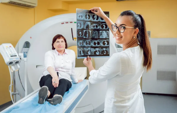 Radiologist with an elderly female patient looking at x-ray. Background