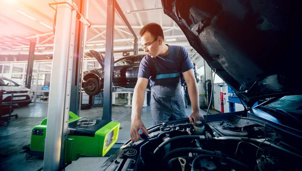 İşçi bir arabanın ışıklandırma sisteminin farlarını kontrol eder ve ayarlar. Otomatik onarım servisi.