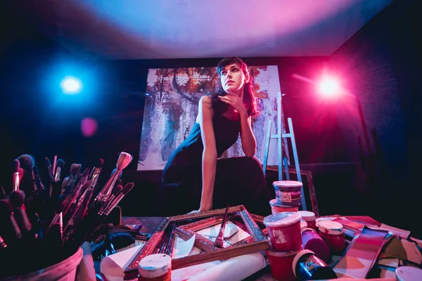 Stüdyoda iş yerinde genç sanatçı. Arka planda büyük tuval