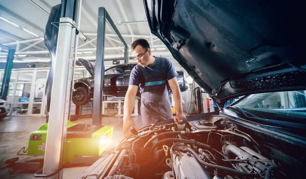 İşçi bir arabanın ışıklandırma sisteminin farlarını kontrol eder ve ayarlar. Otomatik onarım servisi.