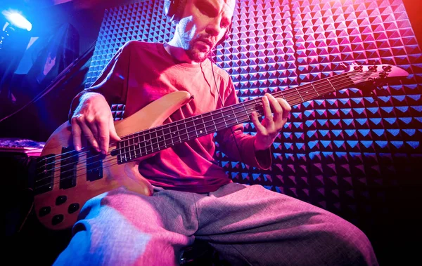 Bas gitar ses kayıt Studio oynayan genç adam. Modern arka plan