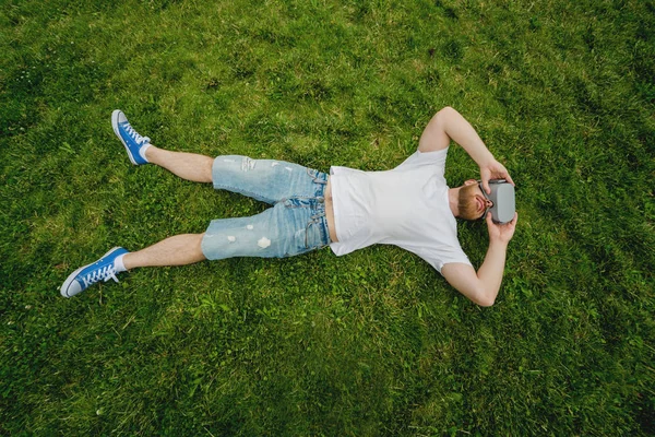 Genç sakallı adam gözlük çim üzerinde yalan sanal gerçekliğin bir oyun oynar. VR kulaklık