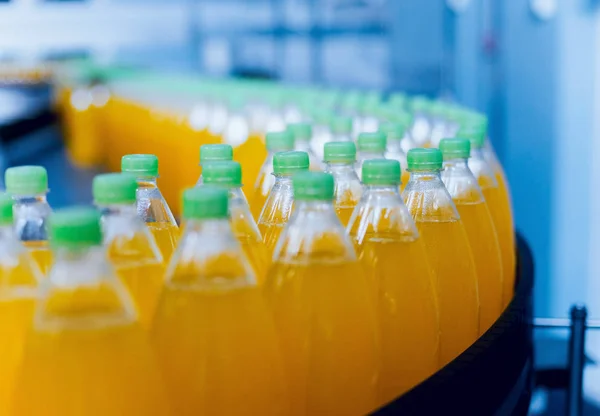 ジュースや水のボトルとコンベヤです 飲料工場の設備機器 バック グラウンド — ストック写真