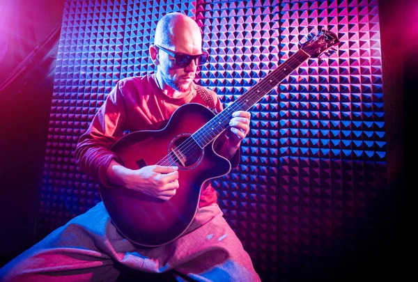 Akustik gitar ses kayıt Studio oynayan genç adam. Modern arka plan