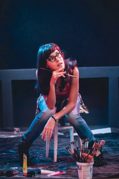 Stüdyoda iş yerinde genç sanatçı. Arka planda büyük tuval