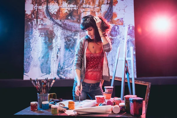 Stüdyoda iş yerinde genç sanatçı. Arka planda büyük tuval