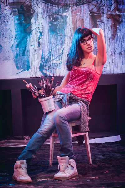 Stüdyoda iş yerinde genç sanatçı. Arka planda büyük tuval