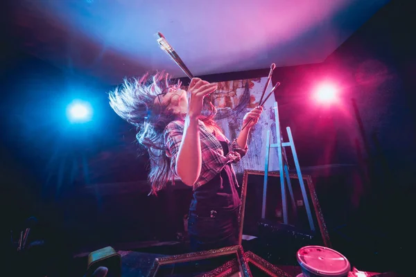 Stüdyoda iş yerinde genç sanatçı. Arka planda büyük tuval