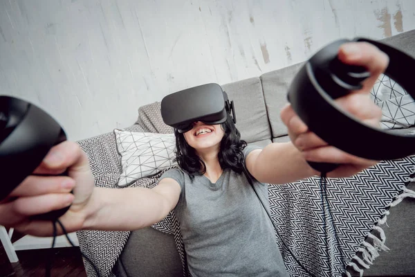 Young girl playing games with virtual reality goggles at home. VR technologies