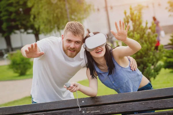 Genç çift sanal gerçeklik gözlükle sokakta bir oyun oynuyor. VR kulaklık.