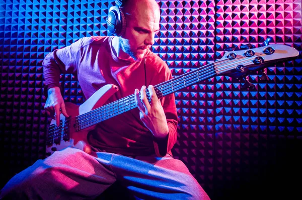 Bas gitar ses kayıt Studio oynayan genç adam. Modern arka plan