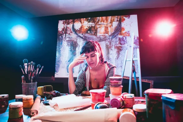 Stüdyoda iş yerinde genç sanatçı. Arka planda büyük tuval