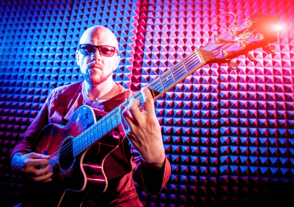 Akustik gitar ses kayıt Studio oynayan genç adam. Modern arka plan