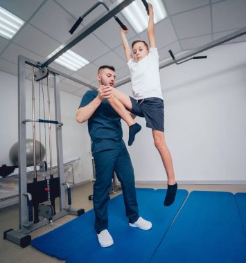 Rehabilitasyon kavramı. Genç çocuk mat fizyoterapist gözetiminde egzersizleri yapıyor. Egzersiz tedavisi