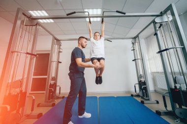 Rehabilitasyon kavramı. Genç çocuk mat fizyoterapist gözetiminde egzersizleri yapıyor. Egzersiz tedavisi