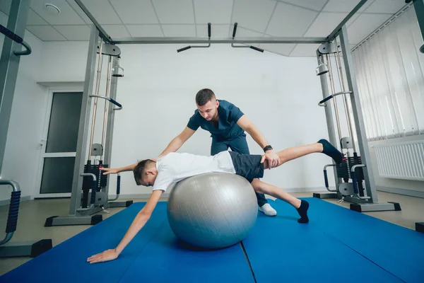 Conceito Reabilitação Jovem Fazendo Exercícios Com Bola Sob Supervisão Fisioterapeuta — Fotografia de Stock