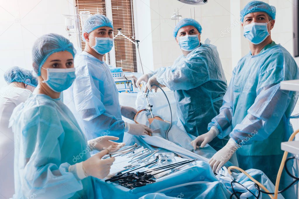 Process of gynecological surgery operation using laparoscopic equipment. Group of surgeons in operating room with surgery equipment. Background