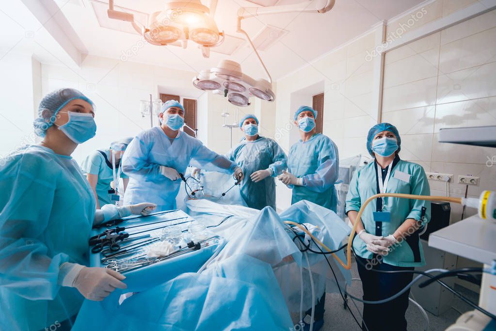 Process of gynecological surgery operation using laparoscopic equipment. Group of surgeons in operating room with surgery equipment. Background