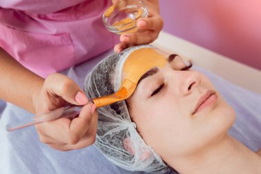 Spa salonda yüz kozmetik prosedür. Güzel bir kadının yüzüne bir maske uygulamak için yordam. Spa uygulamaları