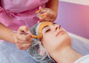 Spa salonda yüz kozmetik prosedür. Güzel bir kadının yüzüne bir maske uygulamak için yordam. Spa uygulamaları