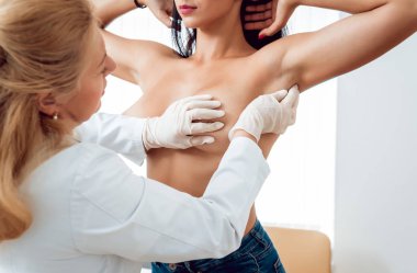 Doktor genç kadının meme incelenmesi olsun. Jinekolog ile istişare. Tanı, sağlık, sağlık hizmeti