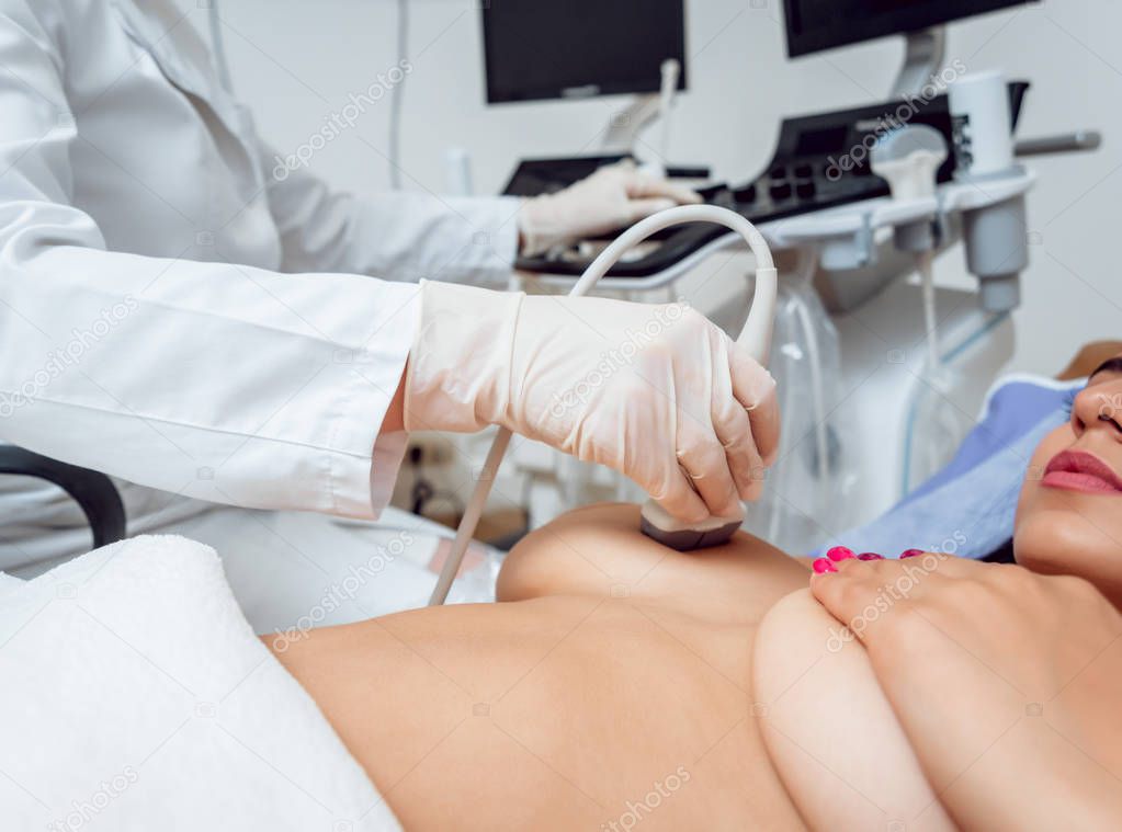Gynecologist performing breast examination for her patient using ultrasound scanner. Sonography. Medical equipment healthcare. Ultrasound scanning. Diagnostic, healthcare, medical service