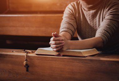 Kilisede dua Hıristiyan kadın. El geçti ve İncil'de ahşap masa üzerinde. Arka plan