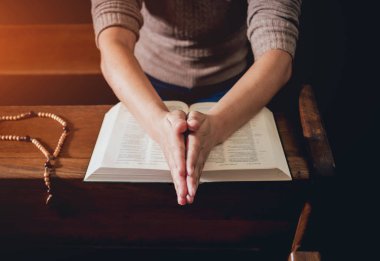 Kilisede dua Hıristiyan kadın. El geçti ve İncil'de ahşap masa üzerinde. Arka plan