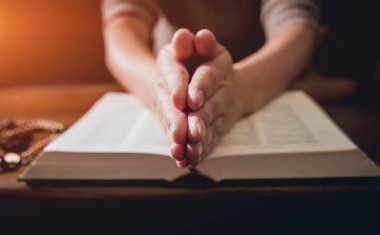 Kilisede dua Hıristiyan kadın. El geçti ve İncil'de ahşap masa üzerinde. Arka plan