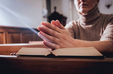 Kilisede dua Hıristiyan kadın. El geçti ve İncil'de ahşap masa üzerinde. Arka plan