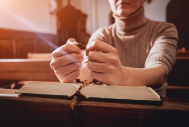 Kilisede dua Hıristiyan kadın. El geçti ve İncil'de ahşap masa üzerinde. Arka plan